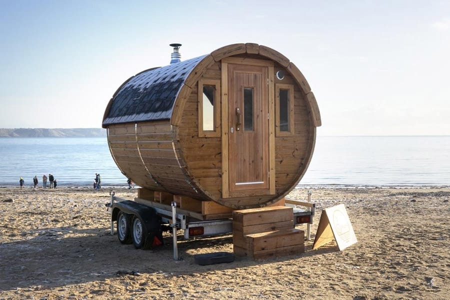 Outdoor cold plunge tub next to portable sauna at lakeside retreat