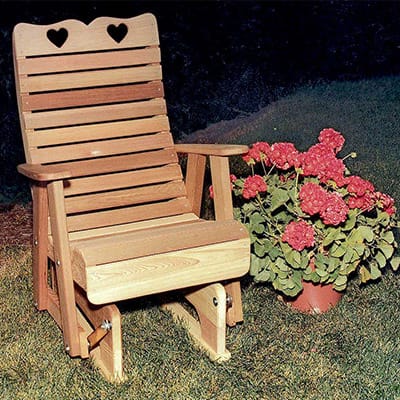 Cedar Royal Country Hearts Glider Chair in garden setting, showcasing honey-brown hue and lumbar support as a charming wood glider for porches.