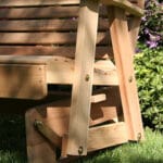 Side profile of durable Cedar Royal Country Hearts Glider Chair, highlighting gliding mechanism, scroll accents, and curved seat in this wood glider for patios.