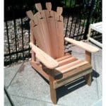 Close-up of wine glass holder on Cedar Adirondack Chair armrest, emphasizing practical design and smooth grain in resilient wood outdoor furniture.
