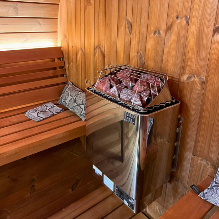 Premium SaunaLife E7G barrel sauna glowing at night with interior lighting